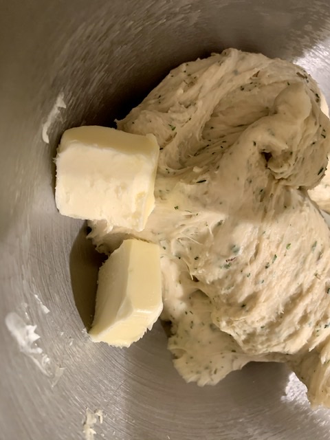 Adding butter to dough for Savory Pesto Cheese Brioche Wreath
